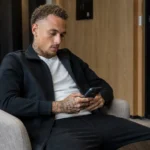 Noa Lang in neutrale sportkleding in een rustige hotellounge.