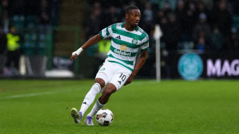 Michel-Ange Balikwisha in een groen-wit gestreept tenue op een nat voetbalveld.
