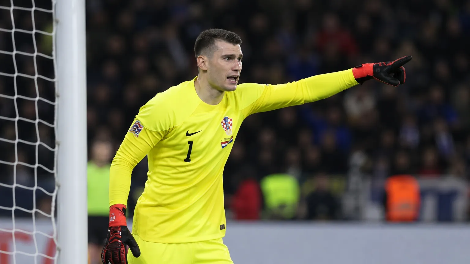 Dominik Livakovic in geel doelmannenpak tijdens een voetbalwedstrijd.