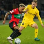 Twee voetballers in actie tijdens een Europees duel op een grasveld.