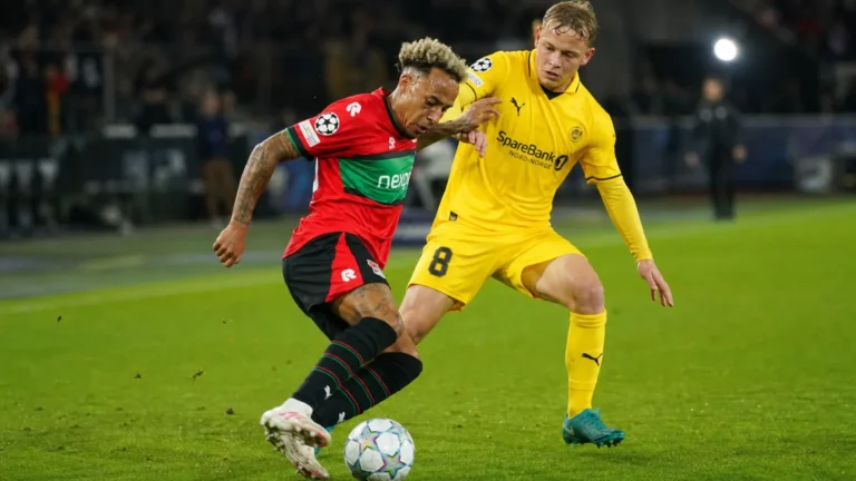 Twee voetballers in actie tijdens een Europees duel op een grasveld.