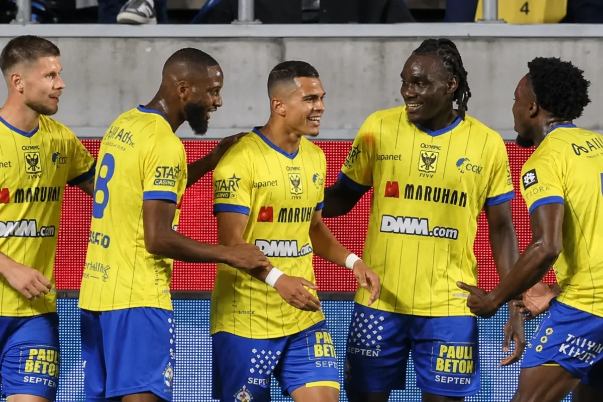 Een groep STVV-spelers viert samen op het veld in gele en blauwe tenues.