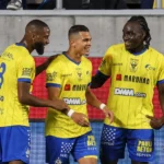 Een groep STVV-spelers viert samen op het veld in gele en blauwe tenues.