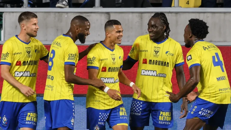 Een groep STVV-spelers viert samen op het veld in gele en blauwe tenues.