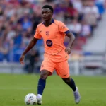 Jesse Bisiwu in een oranje Barcelona-tenue tijdens een voetbalactie op het veld.
