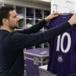 Een stafmedewerker hangt een RSC Anderlecht-shirt met nummer tien in een materiaalruimte.