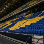 Een lege tribunesectie met nieuwe blauwe en gele zitjes in het stadion van STVV.