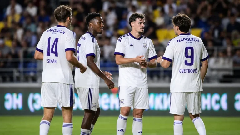 Anderlecht-spelers in witte wedstrijdtenues groeperen zich tijdens een Europese uitwedstrijd.