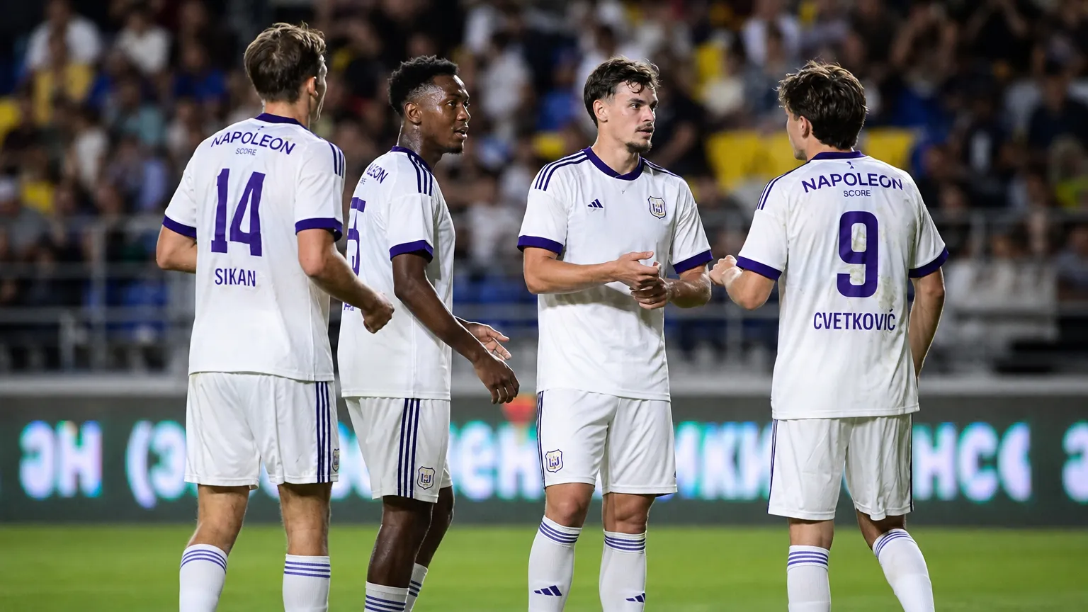 Anderlecht-spelers in witte wedstrijdtenues groeperen zich tijdens een Europese uitwedstrijd.