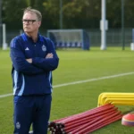 Piet Erauw staat met trainingsmateriaal op een voetbalveld.