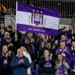Supporters van RSC Anderlecht vieren in de tribune met paars-witte vlaggen.