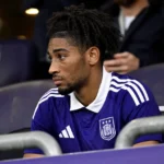 Een Anderlecht-speler kijkt vanaf de tribune naar het veld tijdens een Europese wedstrijd.