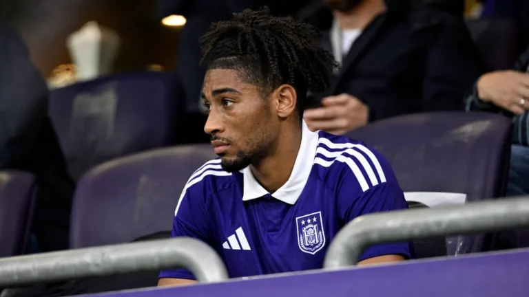 Een Anderlecht-speler kijkt vanaf de tribune naar het veld tijdens een Europese wedstrijd.