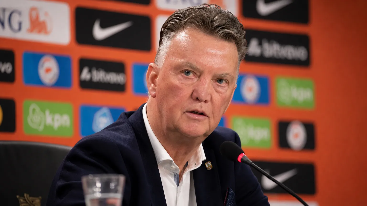 Louis van Gaal tijdens een neutraal persmoment in een voetbalmediaomgeving.