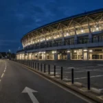 Toegangsweg en parkeerzone langs een voetbalstadion in de avond