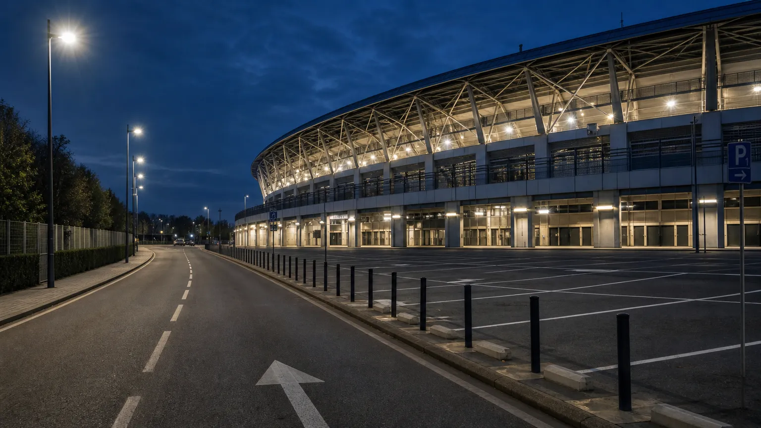Toegangsweg en parkeerzone langs een voetbalstadion in de avond