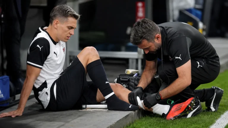 Leandro Trossard krijgt verzorging aan zijn enkel naast het veld.