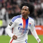 Malick Fofana in een wit Lyon-shirt tijdens een voetbalmoment op het veld.
