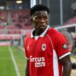 Jules Ahoka in het rood van Royal Antwerp FC langs de zijlijn van een stadion.