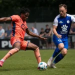 Twee voetballers strijden om de bal op een grasveld.
