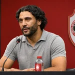 Marvin Compper spreekt in een persruimte met een discreet embleem van Royal Antwerp FC op de achtergrond.
