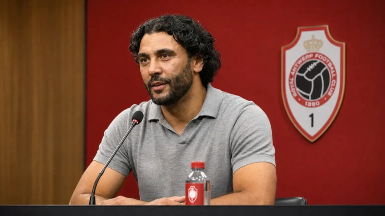 Marvin Compper spreekt in een persruimte met een discreet embleem van Royal Antwerp FC op de achtergrond.