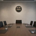 Een formele vergaderruimte met een discreet FIFA-embleem aan de wand.