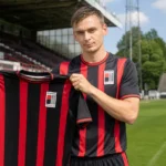 Jasper Van Oudenhove toont een RWDM-shirt in het Edmond Machtensstadion.