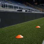 Opwarmzone naast een voetbalveld met kegels en een discreet Club Brugge-bord.