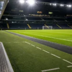 Een verlicht Europees voetbalveld met technische zone voor een returnwedstrijd.