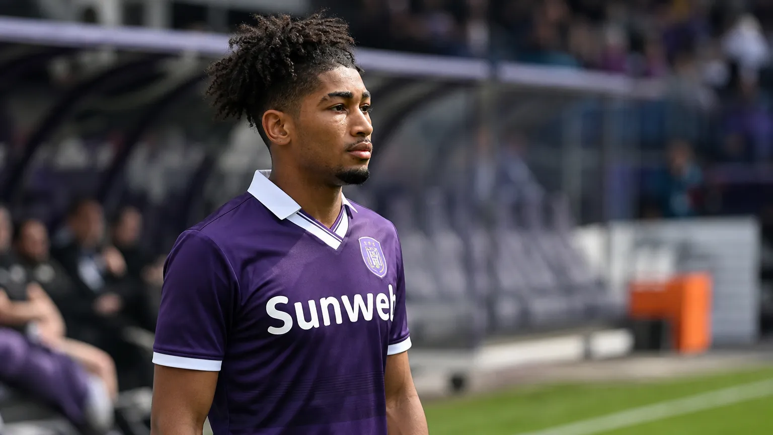 Nathan-Dylan Saliba in een paars voetbalshirt langs de zijlijn van een stadion.
