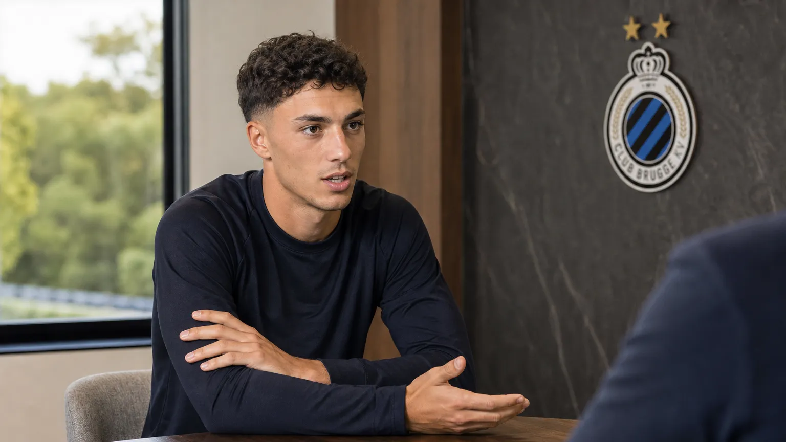 Jan Virgili tijdens een rustig interviewmoment in een Club Brugge-mediaomgeving.