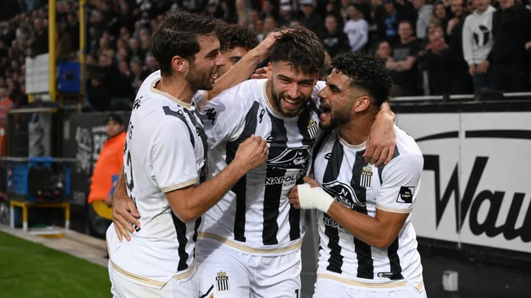 Spelers van Sporting Charleroi vieren samen een doelpunt aan de zijlijn.