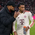 Een Bayern München-coach en een speler overleggen langs het veld tijdens een wedstrijd.