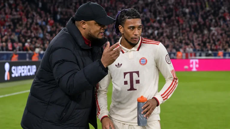 Een Bayern München-coach en een speler overleggen langs het veld tijdens een wedstrijd.
