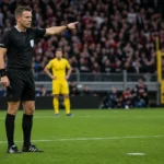 Een scheidsrechter wijst op het strafschoppunt tijdens een voetbalwedstrijd.