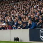 Supporters in een stadiontribune naast een vast Bordeaux-clubbanner.