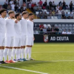 Spelers van AD Ceuta staan schouder aan schouder bij de aftrap in het Murube-stadion.
