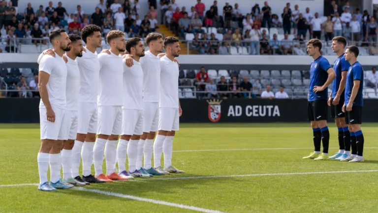 Spelers van AD Ceuta staan schouder aan schouder bij de aftrap in het Murube-stadion.