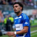 Tristan Gooijer in een blauw voetbalshirt langs de rand van een veld.