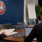 Anonieme medewerkers bekijken documenten in een administratieve UEFA-omgeving.