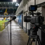 Een televisiecamera en microfoon in de mixed zone van een voetbalstadion.