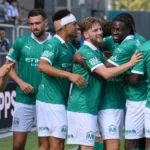 Een groep Lommel-spelers viert samen naast het veld na een thuiswedstrijd.