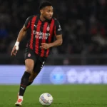Christopher Nkunku in een rood-zwart gestreept voetbaltenue op het veld.