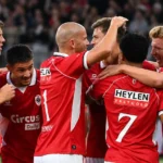 Een groep spelers van Royal Antwerp FC viert samen op het veld.