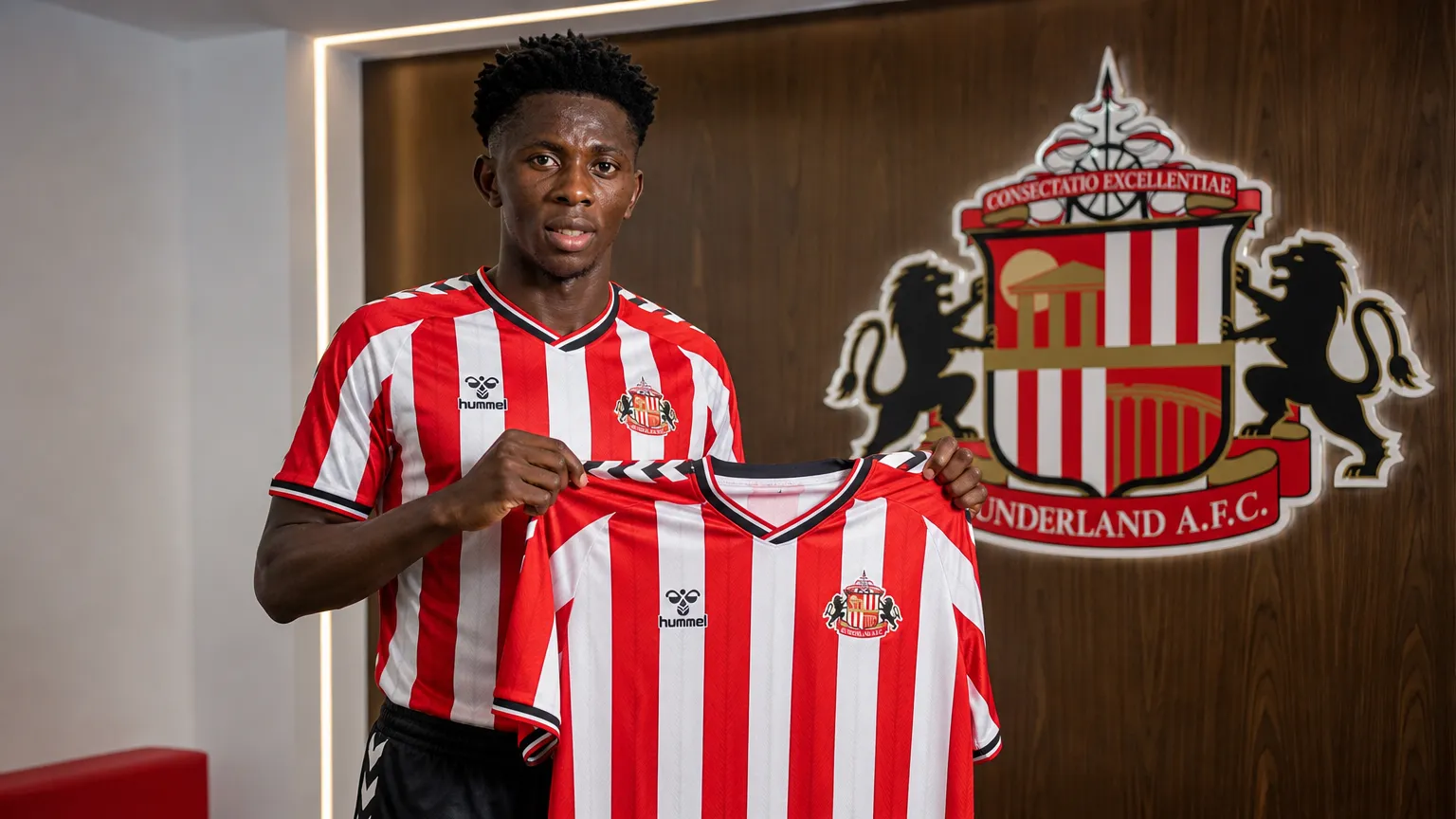 Jules Ahoka toont een Sunderland-shirt tijdens een officiële clubpresentatie.