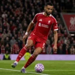 Cody Gakpo in Liverpool-tenue tijdens een actie voor doel op een voetbalveld.