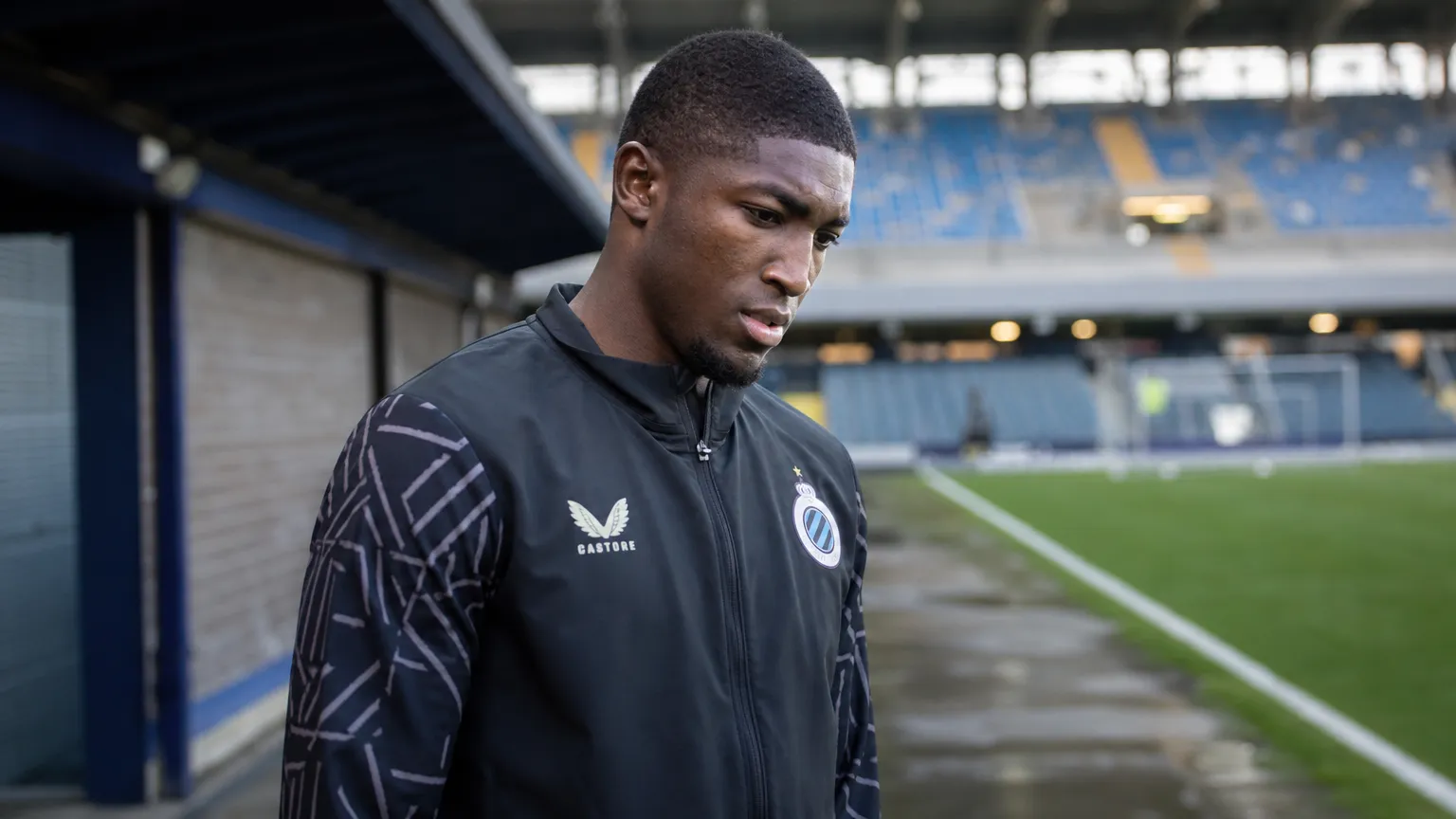 Joel Ordoñez in een zwarte trainingsjas van Club Brugge naast het veld.
