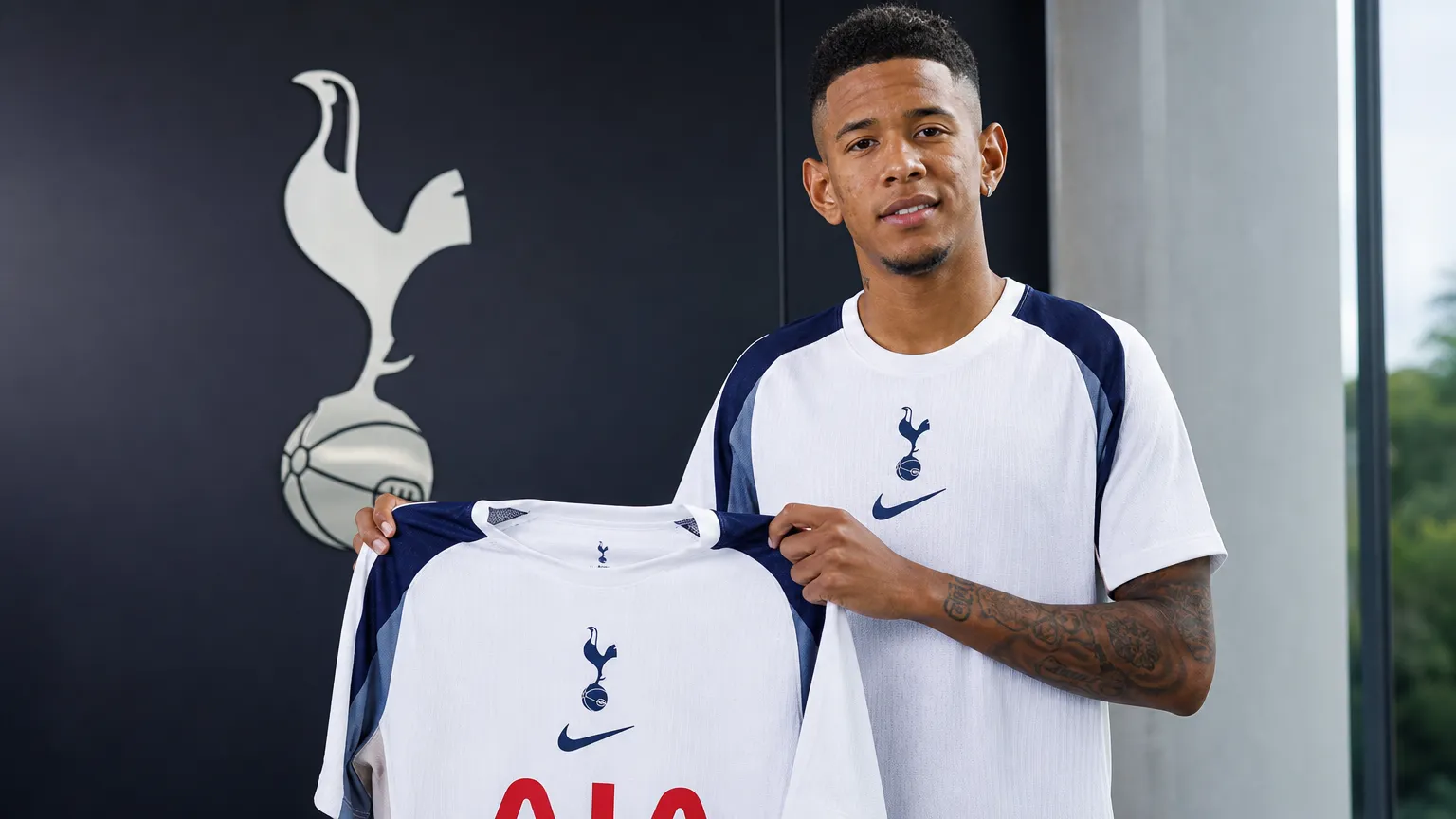 Savinho poseert met een Tottenham-shirt tijdens zijn officiële presentatie.