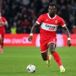 Marwan Al-Sahafi in een rood wedstrijdtenue tijdens een voetbalactie.